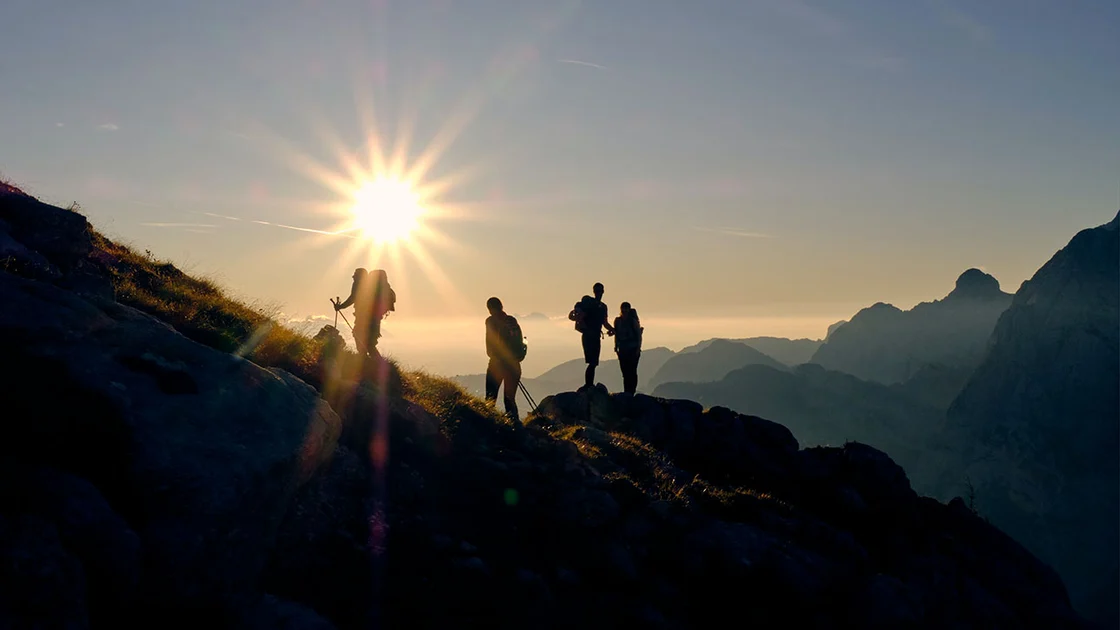 Ragazzi che stanno scalando una montagna, mentre sta tramontando